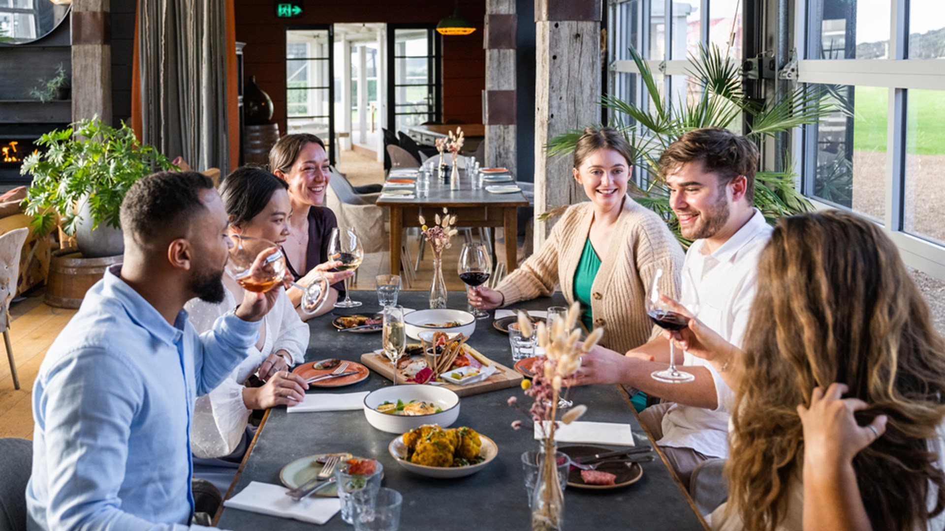 Group of friends clinking glasses at a sunlit table inside Batch Winery.jpg