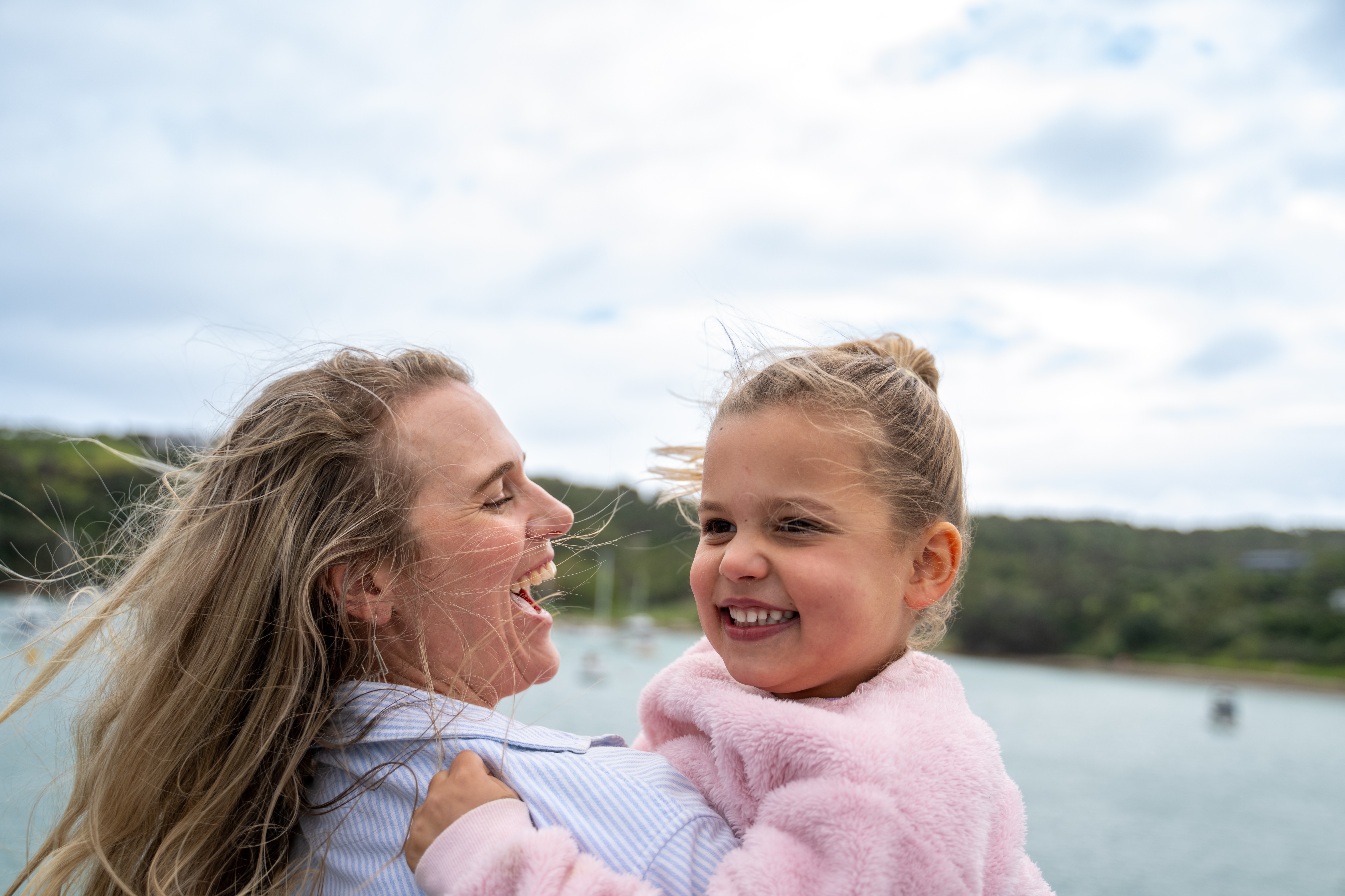 Mother and daughter laughing together by the water on Waiheke Island, perfect Mother’s Day family moment